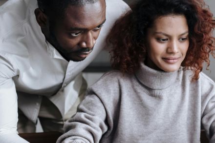 A diverse couple working together on a laptop in a cozy home setting, showcasing teamwork and technology.