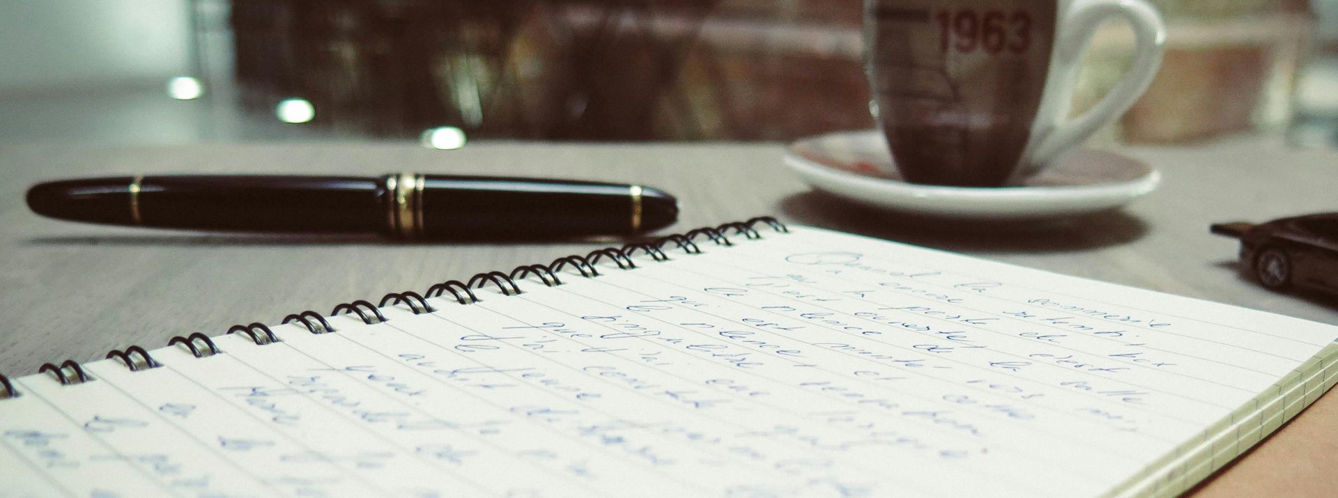 A warm, inviting workspace featuring coffee, handwritten notes, and a pen on the desk.