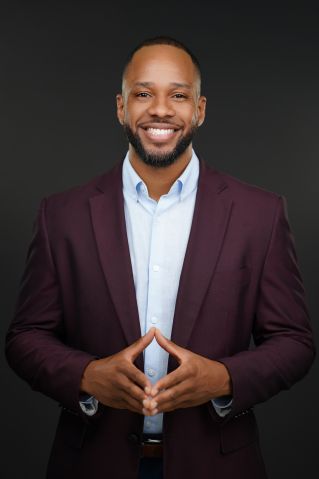 Smiling black businessman holding documents in a modern office setting.